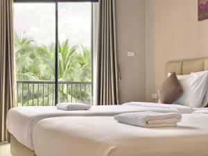 two beds in a hotel room with a large window at The Coconut Hotel in Lampang