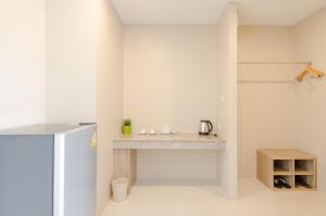 a white kitchen with a counter and a refrigerator at The Coconut Hotel in Lampang