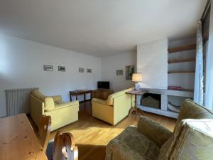 ピンツォーロにあるAppartamenti Residenza Alpinaのリビングルーム(黄色の家具、暖炉付)