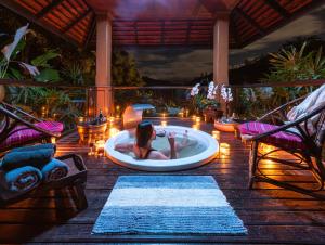 a woman in a bath tub on a deck with lights at Kanlaya's Eyrie, Luxury Homestay in Pang Mapha