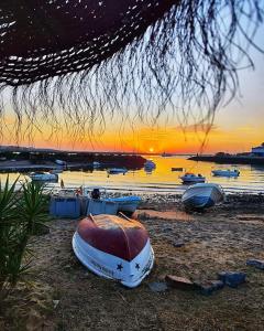 un gruppo di barche sedute sulla spiaggia al tramonto di Sol y Sombra Apartamento con entrada independiente a Isla del Moral