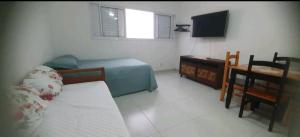 ein Schlafzimmer mit einem Bett, einem Schreibtisch und einem Fernseher in der Unterkunft Aconchegante no Condomínio da Fê in Cachoeira Paulista