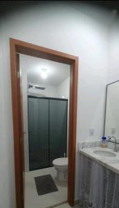 ein Badezimmer mit Toilette, Waschbecken und Spiegel in der Unterkunft Aconchegante no Condomínio da Fê in Cachoeira Paulista