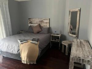 a bedroom with a bed with a mirror and a table at Cosy and Serene Environment in Boksburg