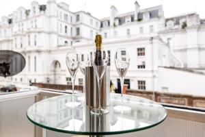 a glass table with a bottle and two wine glasses at Sea Downs - moments from beach in Eastbourne