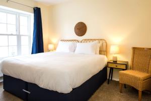 a bedroom with a large white bed and a chair at Sea Downs - moments from beach in Eastbourne