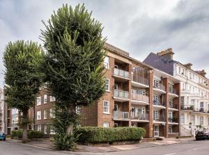 an apartment building with a tree in front of it at Sea Downs - moments from beach in Eastbourne