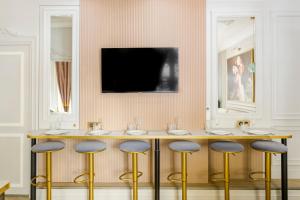 um bar com bancos e uma televisão na parede em Luxury 2 bedroom & 2 bathroom - Marais & Louvre em Paris