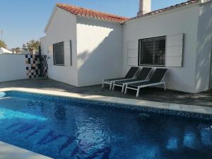 a swimming pool with two chairs next to a house at Belvilla by OYO Blissful Villa with Private Pool in Isla Cristina