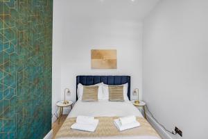 um quarto com uma cama com uma cabeceira azul e duas mesas em Modern 3 and 2 bedroom apartment in Maida Vale em Londres