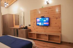 ein Schlafzimmer mit einem TV an einer Holzwand in der Unterkunft The Lake Ambience Resort in Bhīm Tāl