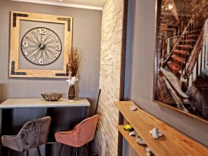 a room with a clock on the wall and chairs at Apartman Kalina in Novi Sad