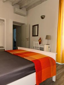 a bedroom with a bed with an orange and red blanket at AM's Apartment in La Spezia