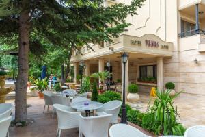 Hotel Venus في ساني بيتش: مقهى والكراسي البيضاء والطاولات أمام المبنى