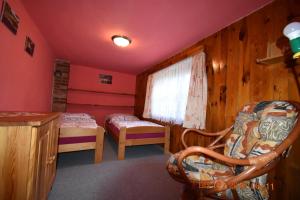 a room with two beds and a chair and a window at Chalupa Alexandra in Kacanovy