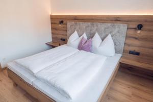a bedroom with a bed with white sheets and pillows at Apart Eder in Schwendau