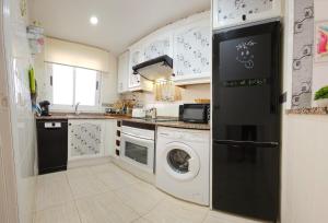 a kitchen with white cabinets and a washer and dryer at Bonito piso en MarinaDor in Castellón de la Plana