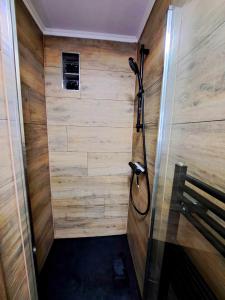 a shower in a room with a wooden wall at petite chambre dans une jolie colocation in Liège