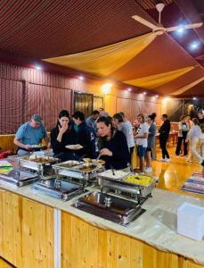 a group of people standing around a buffet of food at camp scylla Wadi Rum in Wadi Rum