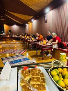 a group of people sitting at tables in a room with food at camp scylla Wadi Rum in Wadi Rum