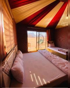 a room with two beds and a large window at camp scylla Wadi Rum in Wadi Rum