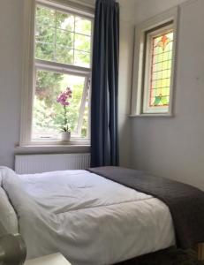 um quarto com uma cama e uma janela com um vaso de flores em Cleddon em Bournemouth