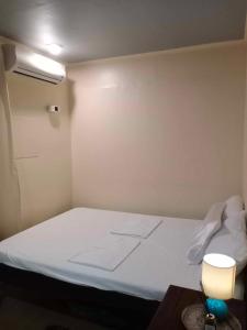 Z&j Transient House في بوتوان: غرفة صغيرة بها سرير أبيض مع مصباح
