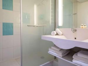 y baño con lavabo y ducha. en Novotel Antibes Sophia Antipolis en Valbonne
