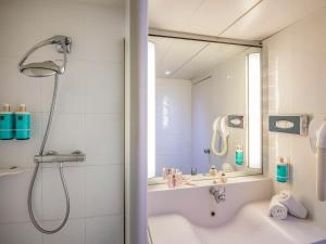 a bathroom with a shower and a tub and a sink at Novotel Antibes Sophia Antipolis in Valbonne