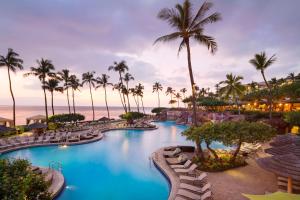 a pool at the resort with palm trees and the ocean at Hyatt Regency Maui Resort & Spa in Lahaina