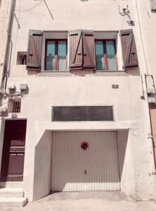 un edificio bianco con una grande porta e finestre di Chez Marie appartement centre historique Perpignan a Perpignano