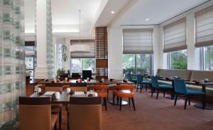 un comedor con mesas, sillas y ventanas en Hilton Garden Inn Jacksonville JTB/Deerwood Park, en Jacksonville