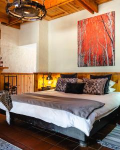 a bedroom with a large bed with a painting on the wall at Anglers Court in Dullstroom
