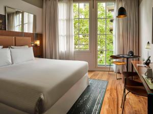 um quarto de hotel com uma cama grande e uma secretária em Hôtel Paris Bastille Boutet - MGallery em Paris