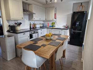 cocina con mesa de madera y nevera negra en Ty Isa en Nefyn