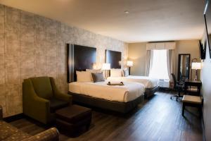 um quarto de hotel com duas camas e uma cadeira em Distill-Inn em Bardstown