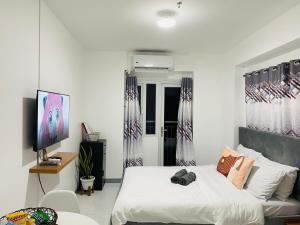 a bedroom with a bed and a tv in it at Condo in EDSA Netflix and SmartTV FreeAccess to POOL and GYM in Manila