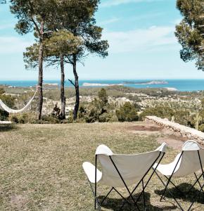 two chairs sitting in a field with the ocean in the background at Blue Hill House, King-of-Hill Villa with amazing scenery, sunset & sea view in San Jose