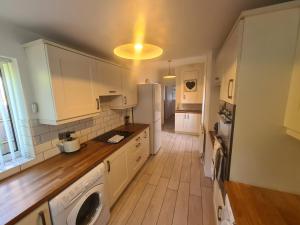 cocina con armarios blancos y nevera blanca en L & J Escapes - 8 Bedrooms suitable for Contractors and Families- Private parking available for 6 vehicles en Coseley