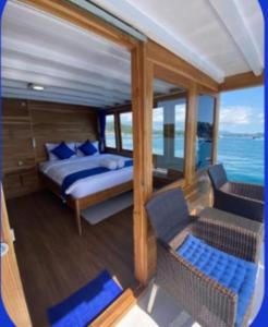 a bedroom on a boat with a bed and a chair at familykomodocruise in Labuan Bajo