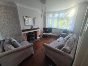 a living room with two couches and a television at L & J Escapes - 8 Bedrooms suitable for Contractors and Families- Private parking available for 6 vehicles in Coseley