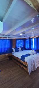a bedroom with two beds on a boat with blue curtains at familykomodocruise in Labuan Bajo
