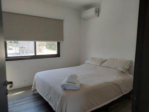 ein weißes Bett in einem Zimmer mit Fenster in der Unterkunft Duplex de Categoria - con estacionamiento gratuito in Cordoba