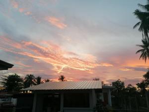 um pôr-do-sol sobre uma casa com telhado e palmeiras em Kathleens Vacation Place em Moalboal