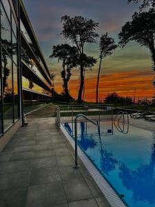a swimming pool in front of a building with a sunset at Apartamenty The View Hevenia in Rewal