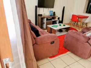 a living room with two brown chairs and a table at 2 Bedroom Apartment in Langata in Nairobi