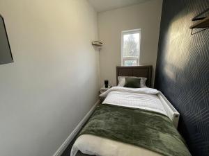 a small bedroom with a bed and a window at Lovely 4 bedroom Victorian house with back courtyard in Stoke on Trent