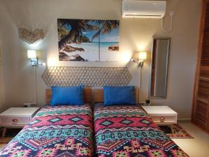 a bedroom with a bed with blue pillows at La Vida Selfcatering Apartements in Mahe