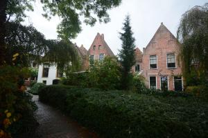 uma fileira de edifícios de tijolos com árvores e um caminho em Goudgenog em Appingedam