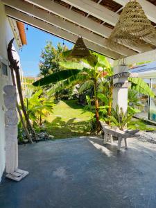 een patio met een bank en een palmboom bij Évasion Tropicale - Villa d'Artiste avec Jacuzzi Privé dans un jardin Exotique in Mérignac